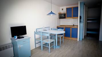 A compact kitchen with a microwave, a small refrigerator, and a dining area with a table and chairs.