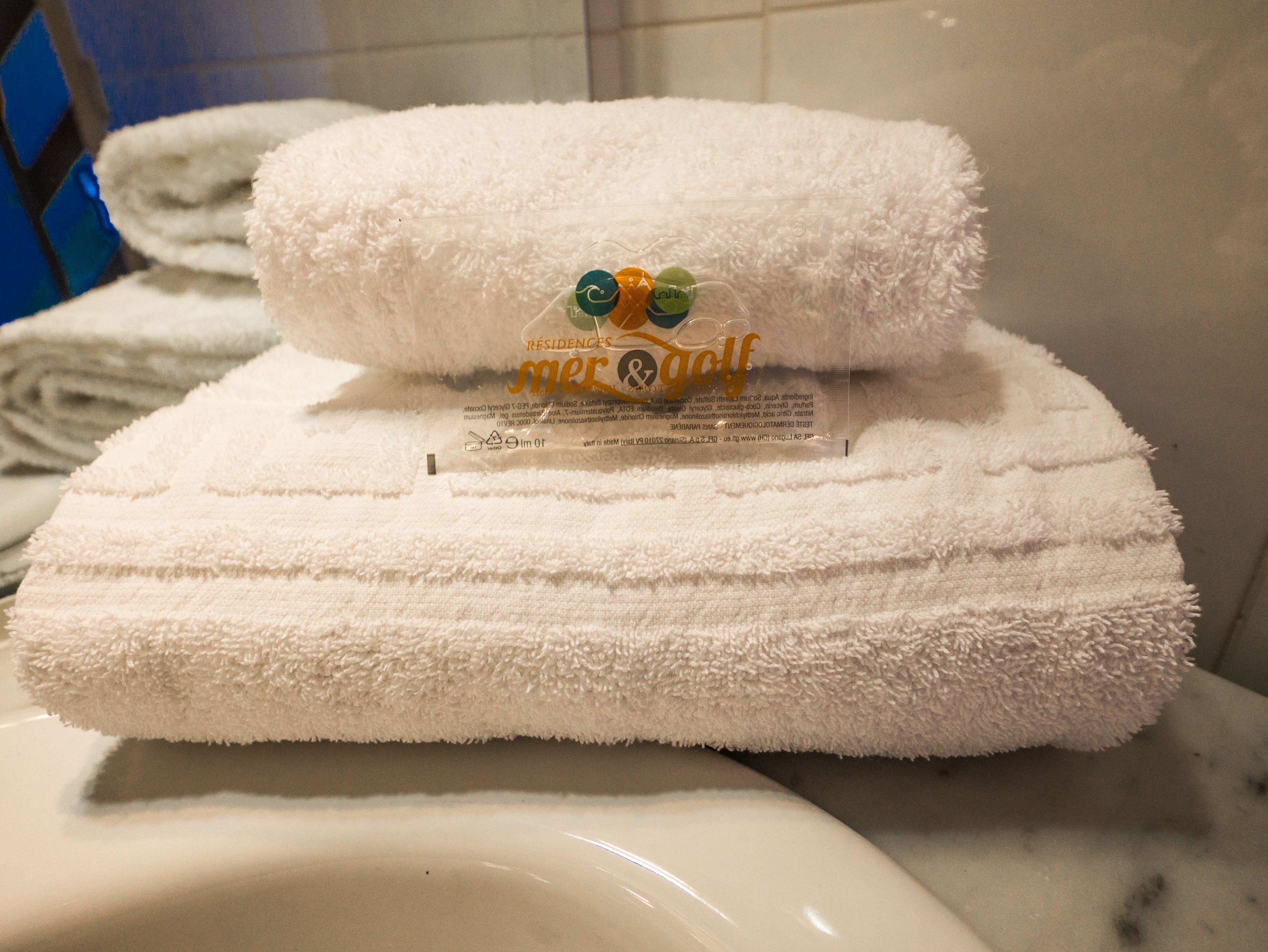 A white towel with a logo and text on it, placed on a white surface.