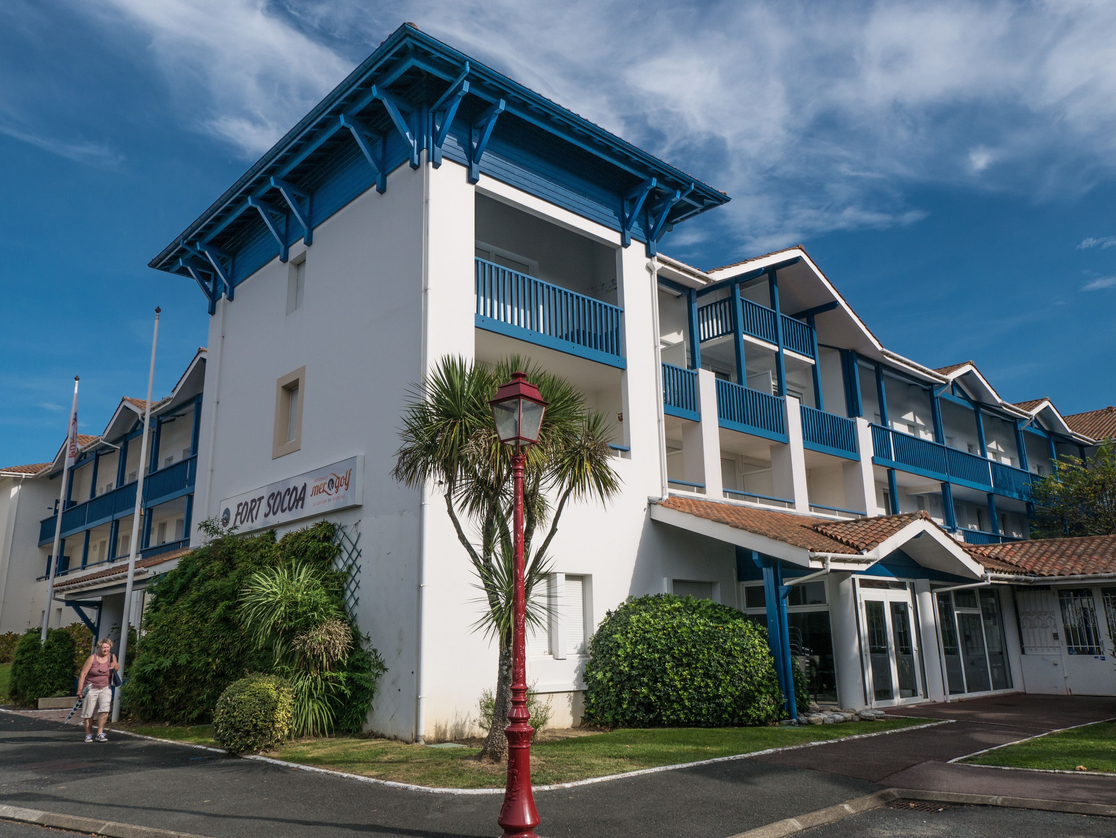 Un hotel con fachada blanca y detalles azules, que cuenta con balcones y un cartel que dice 'Fort Sokol'.