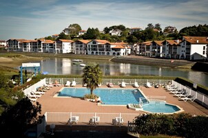 A swimming pool with lounge chairs and a view of a river and buildings in the background.