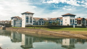 A waterfront hotel with multiple buildings, a canal, and a grassy area. - Résidence Fort Socoa (Urrugne)