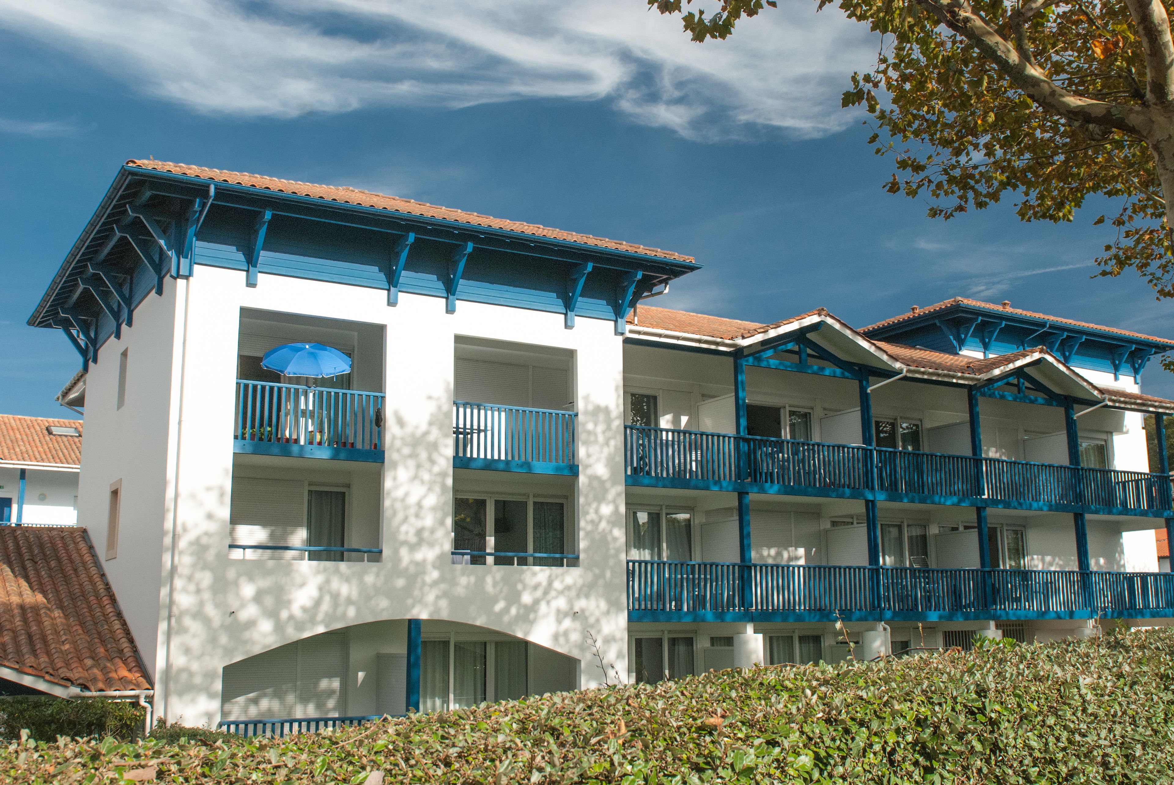 A multi-story hotel with balconies and a tiled roof.