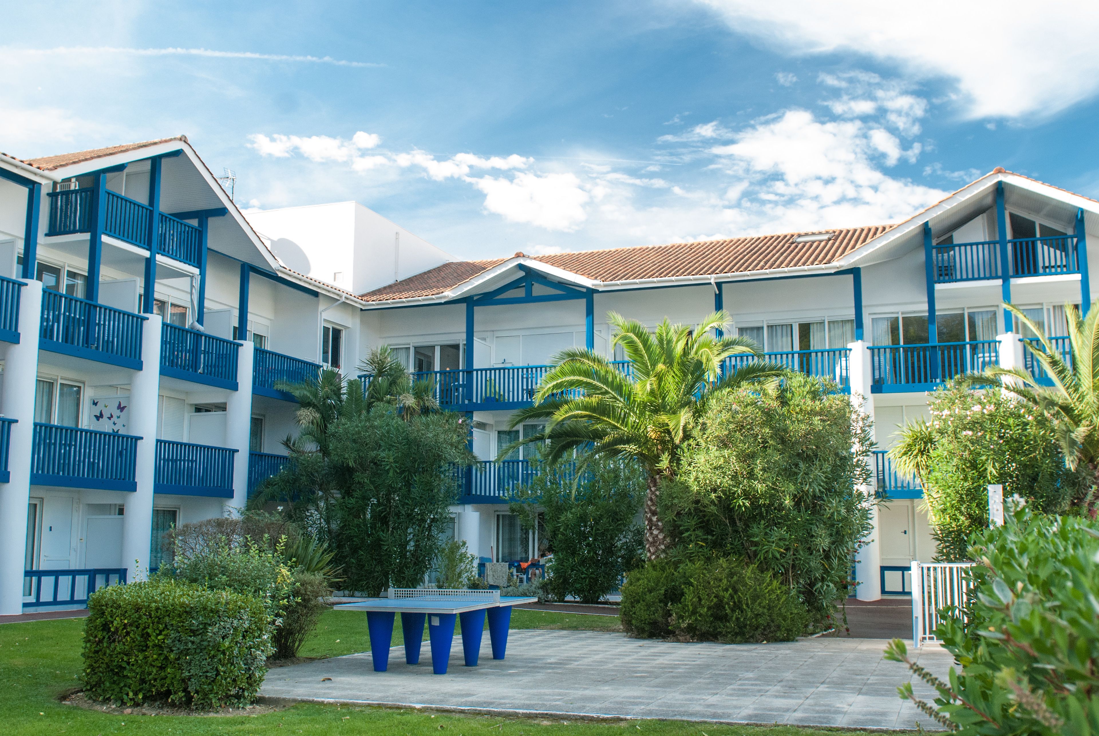 Un hôtel à plusieurs étages doté de balcons, d’une cour intérieure et de palmiers.