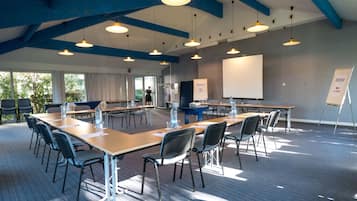 A conference room with long tables, chairs, and a whiteboard.