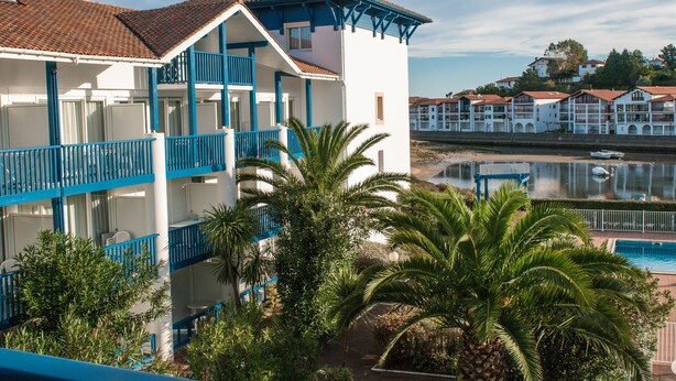 A hotel with multiple balconies, a pool, and a view of the water. - Résidence Fort Socoa (Urrugne)