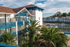 A hotel with multiple balconies, a pool, and a view of the water. - Résidence Fort Socoa (Urrugne)