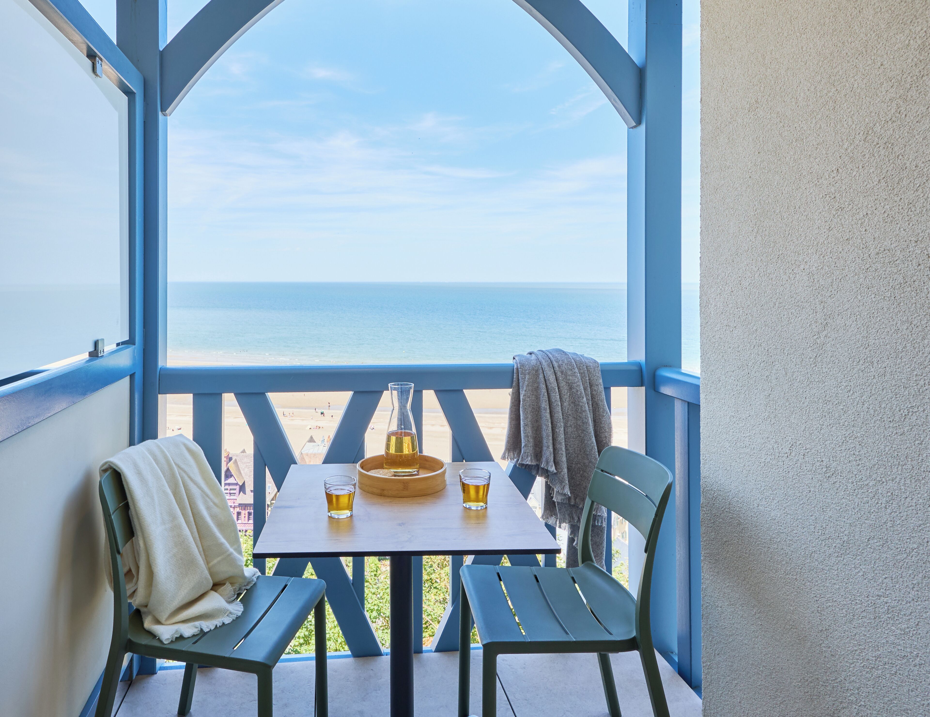 Ein Balkon mit Tisch, zwei Stühlen, einer Flasche und Gläsern.