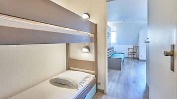 A bunk bed room with a door leading to a living area.