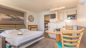 Habitación de hotel con cama, mesa de comedor, televisión, microondas y zona de cocina.