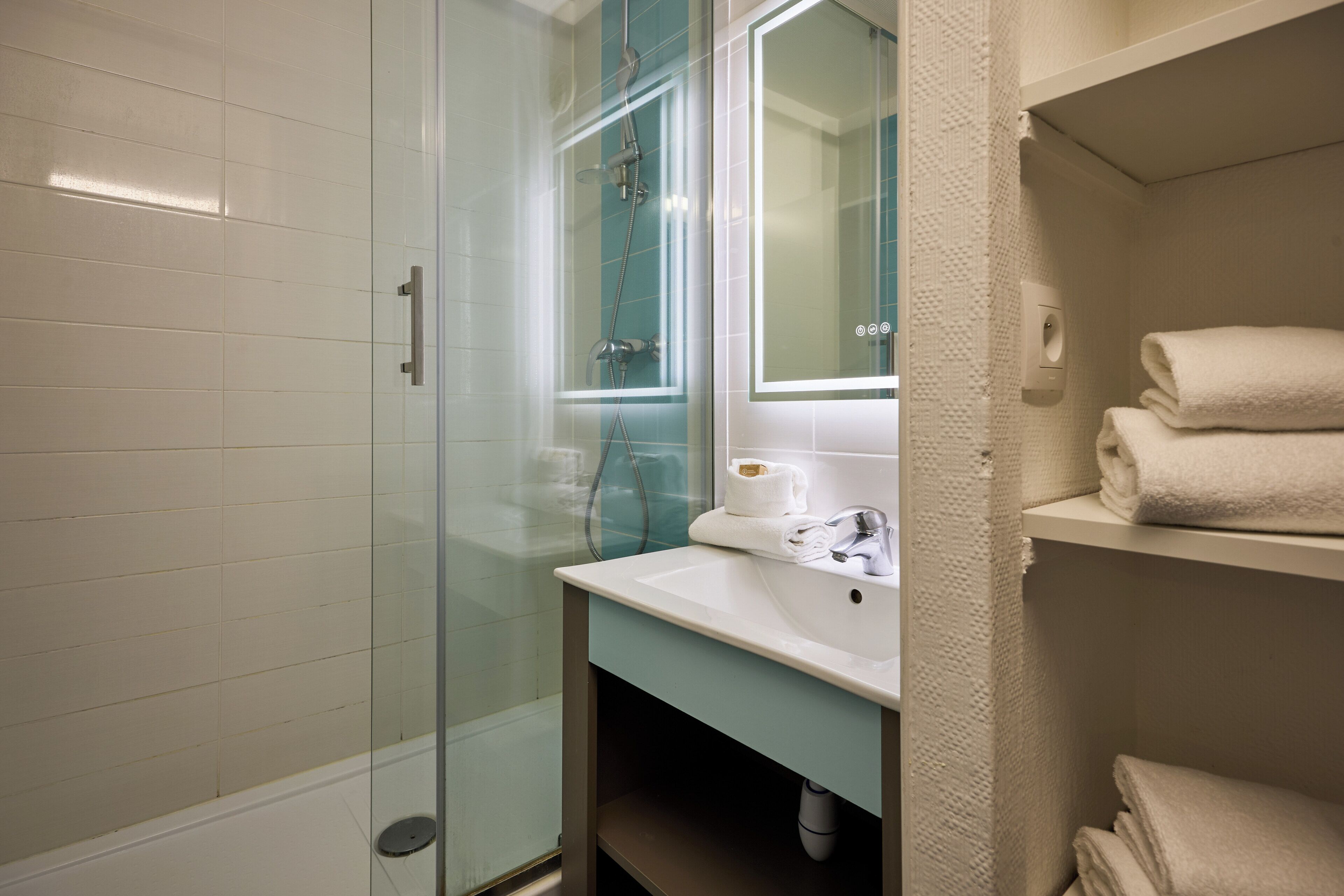 A bathroom with a glass shower enclosure, a white sink with a mirror, and a towel rack.