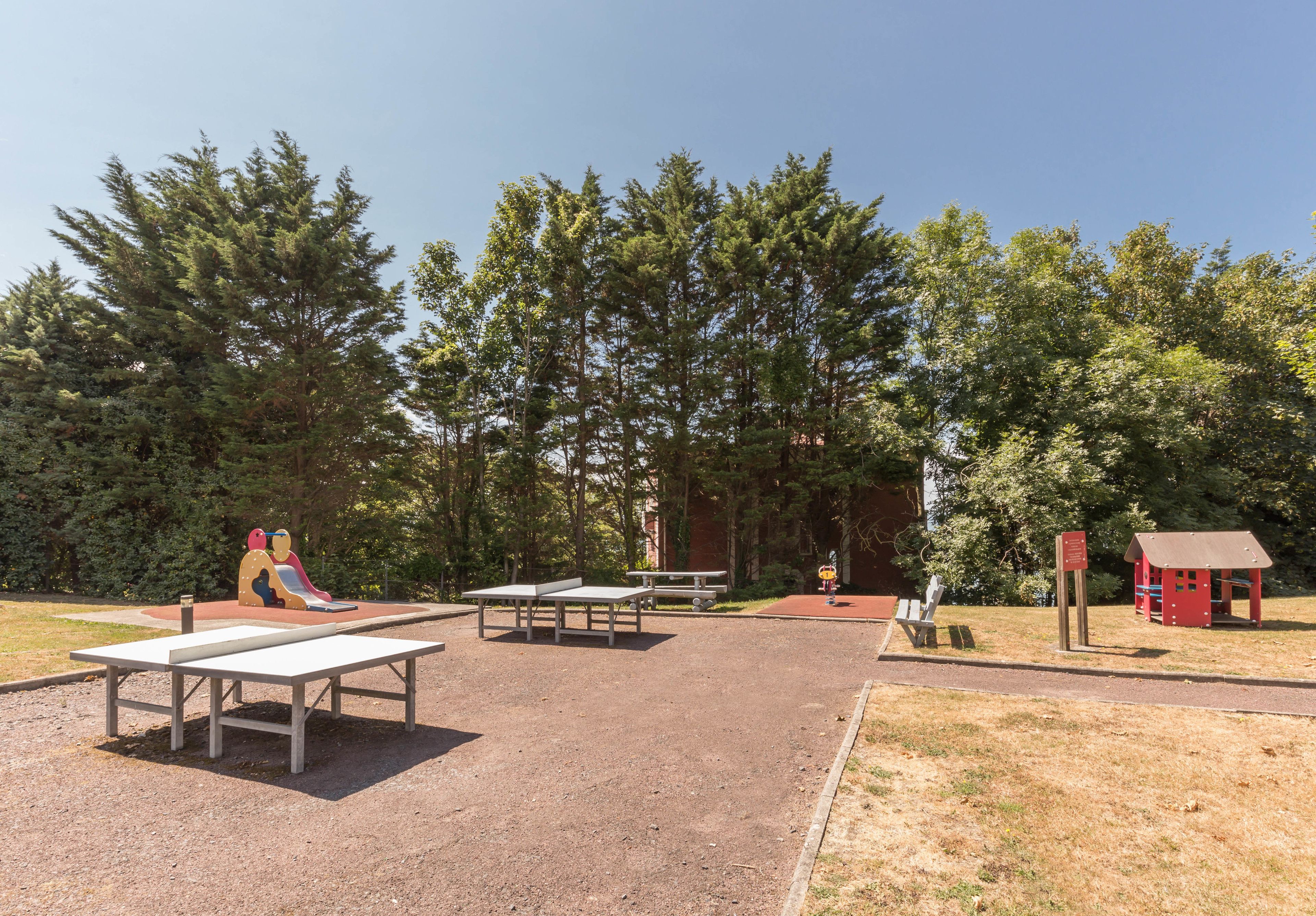 Un patio de juegos al aire libre con mesas y un tobogán.