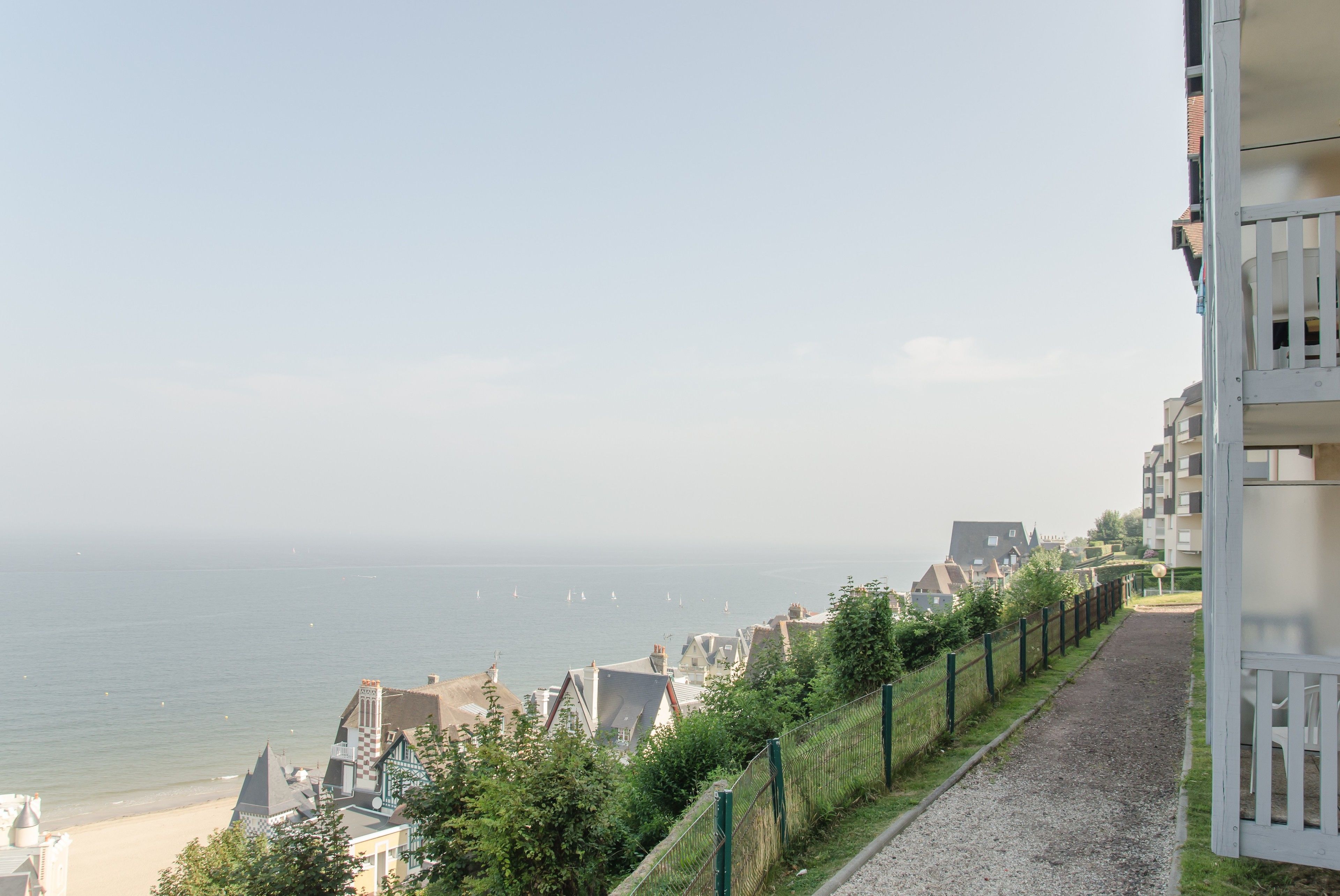 A coastal residential area with a gravel path, houses, and a view of the sea.