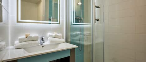 A bathroom with a white sink, a mirror, a glass shower enclosure, and a towel rack.