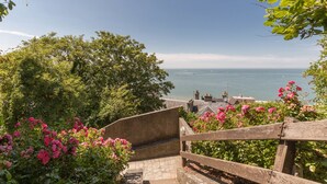 Una escalera que lleva a un mirador con vistas al mar y edificios a lo lejos.