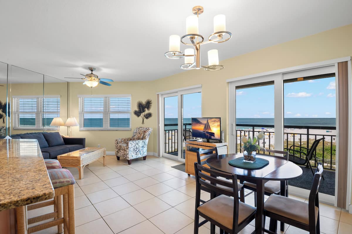 A spacious living area with a balcony, a dining table, and a television.
