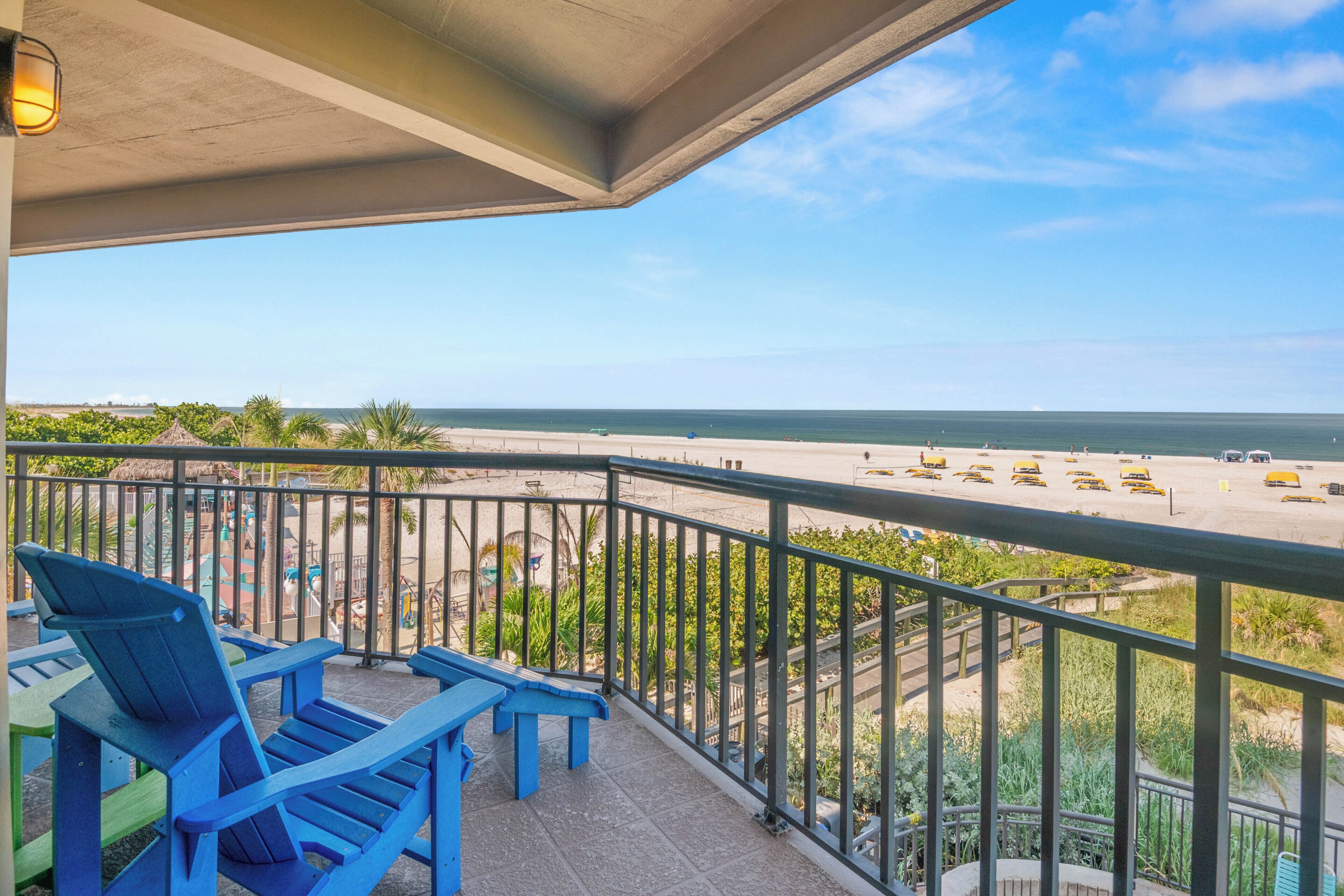 Een balkon met blauwe stoelen en uitzicht op het strand.