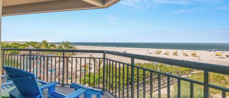 Een balkon met blauwe stoelen en uitzicht op het strand.