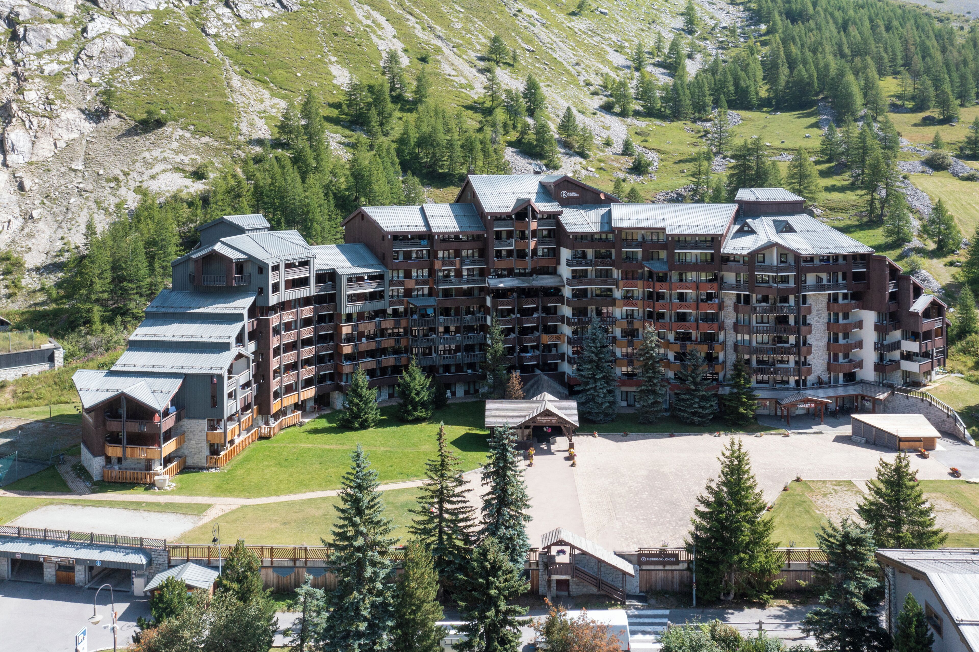 A multi-story hotel with balconies, a central courtyard, and a mountainous backdrop.