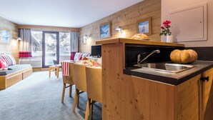 Un espacio habitable compacto con kitchenette, comedor y sofá.