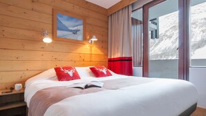 Habitación con paneles de madera, una cama, dos lámparas de pared, una ventana con cortinas e imagen enmarcada en la pared.