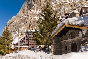 A mountain lodge with a stone facade, wooden balconies, and snow-covered surroundings.