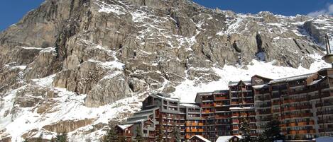 A mountain lodge with multiple floors, wooden exterior, and snow-covered surroundings.