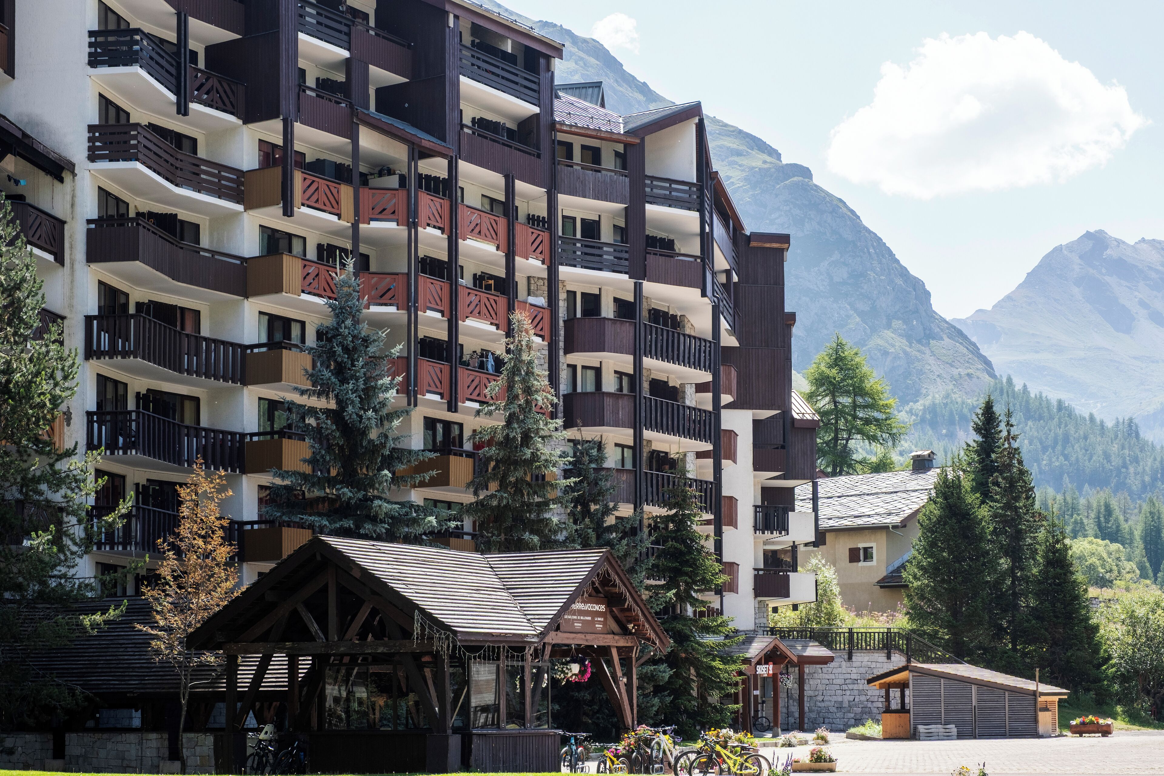Un hotel amb diversos pisos, balcons, estil de xalet de muntanya i vistes a les muntanyes.