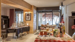 A dining area with a checkered tablecloth, various food items, and a wooden interior. - Résidence Pierre & Vacances La Daille (Val-d'Isere)