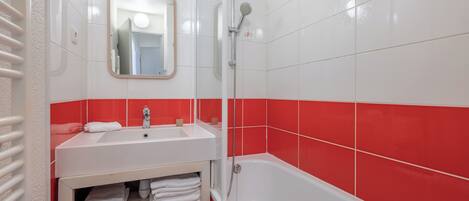 A bathroom with a white sink, a mirror, a shower, and red-tiled walls.