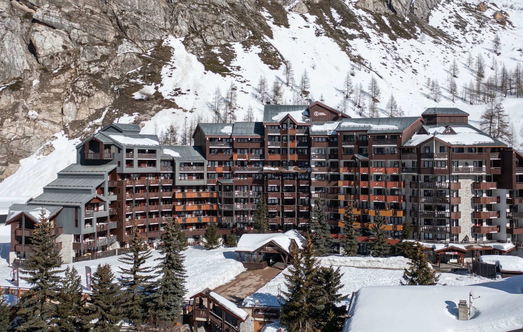Een meerhoog hotel met een skigebied op de achtergrond.
