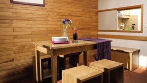 A wooden-paneled room with a table set for dining, a bench, and a mirror on the wall.