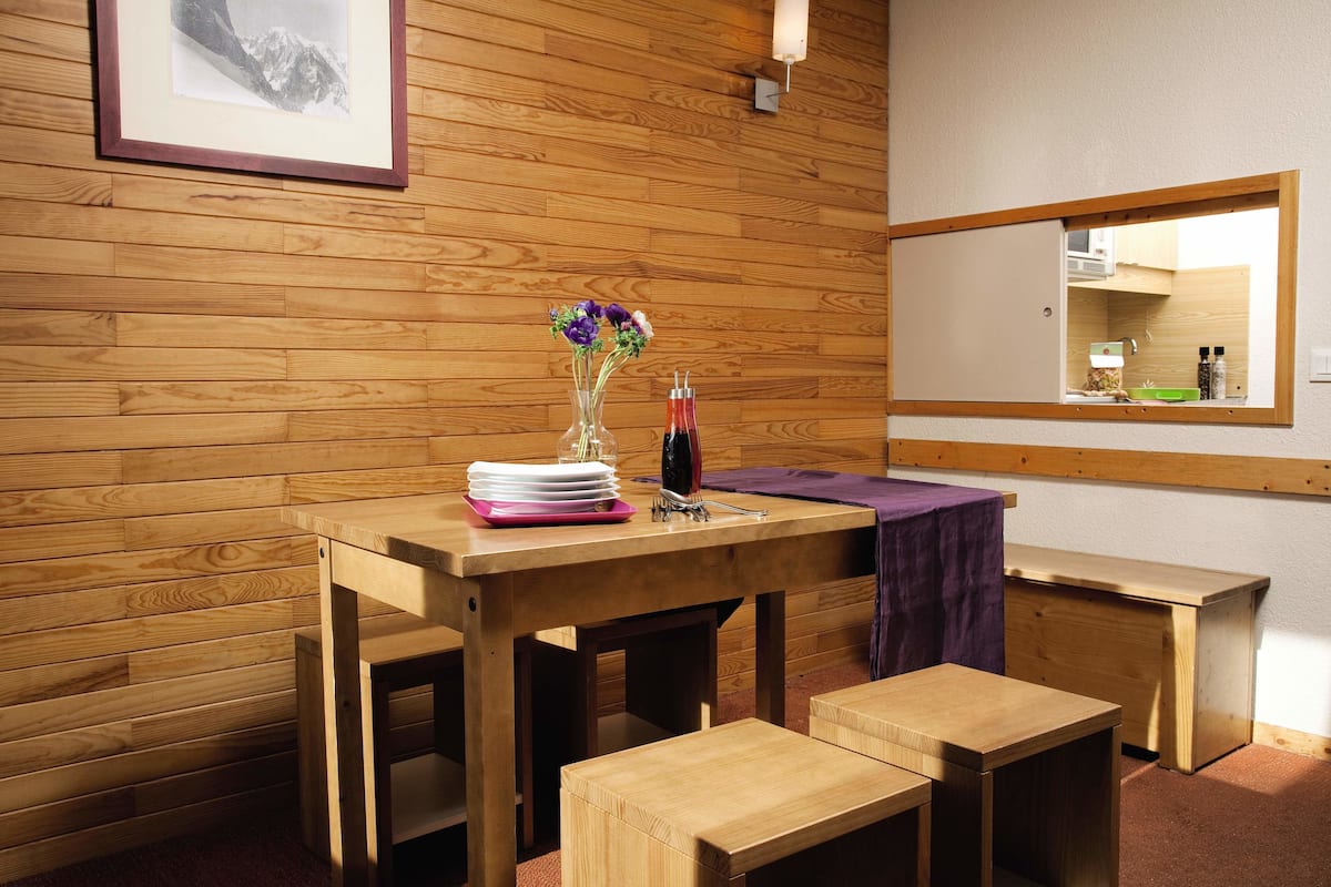 Ein Zimmer mit Holzwänden, gedecktem Tisch, einer Bank und einem Spiegel an der Wand.