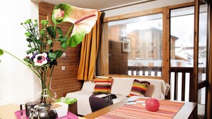 A cozy room with a bed, a table with a vase of flowers, and a window with curtains.