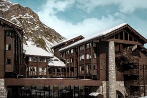 A multi-story wooden building with stone accents, large windows, and a balcony area.