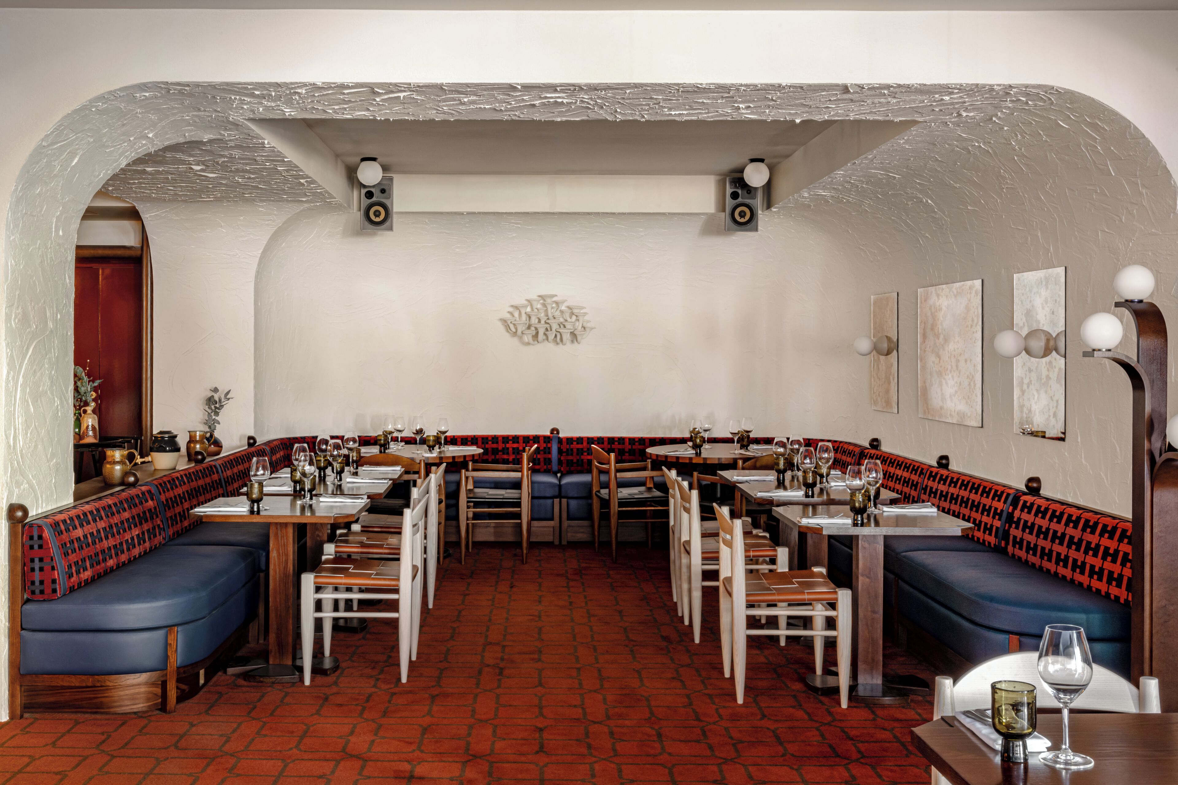 Interno di un ristorante con cabine, tavoli e un pavimento decorato.