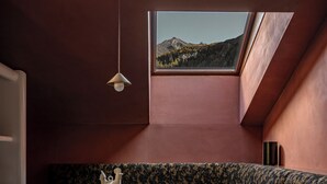 Una habitación acogedora con un banco curvo, una mesa de madera y una ventana pequeña con vistas a un paisaje montañoso.