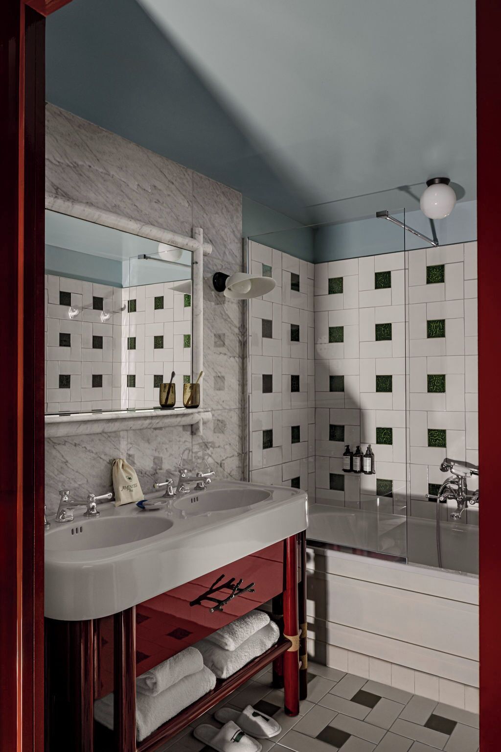 A modern bathroom with two sinks, a large mirror, and a bathtub.