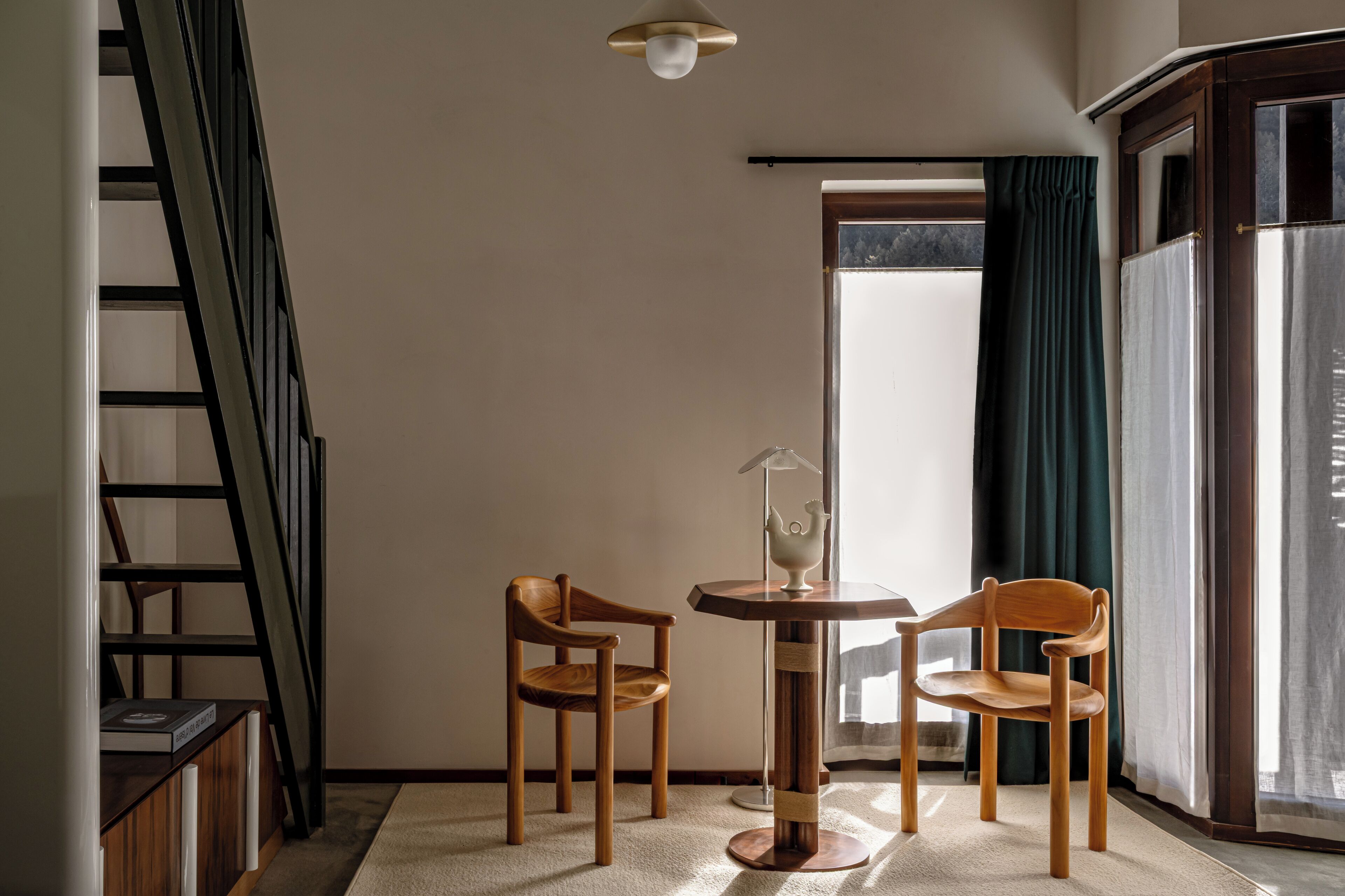 Une pièce d’angle avec une chaise en bois, une petite table ronde et une lampe.
