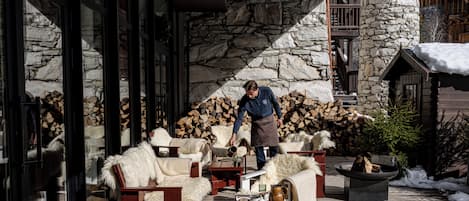 Un rincón al aire libre acogedor con paredes de piedra, muebles de madera y una chimenea.