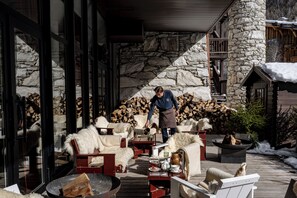 Un rincón al aire libre acogedor con paredes de piedra, muebles de madera y una chimenea.