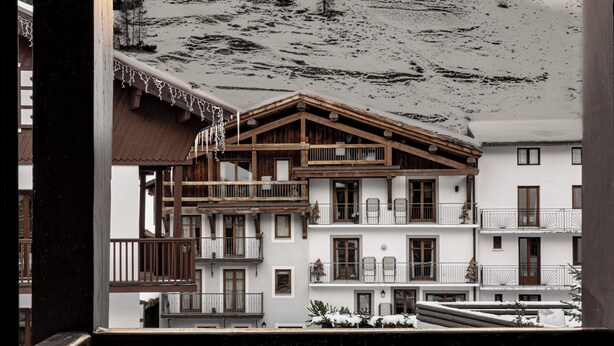 Un hotel con balcón con vistas a un paisaje montañoso nevado.