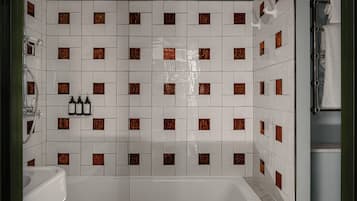 A bathroom with white tiles and brown accents, a bathtub, a sink, and a towel rack.
