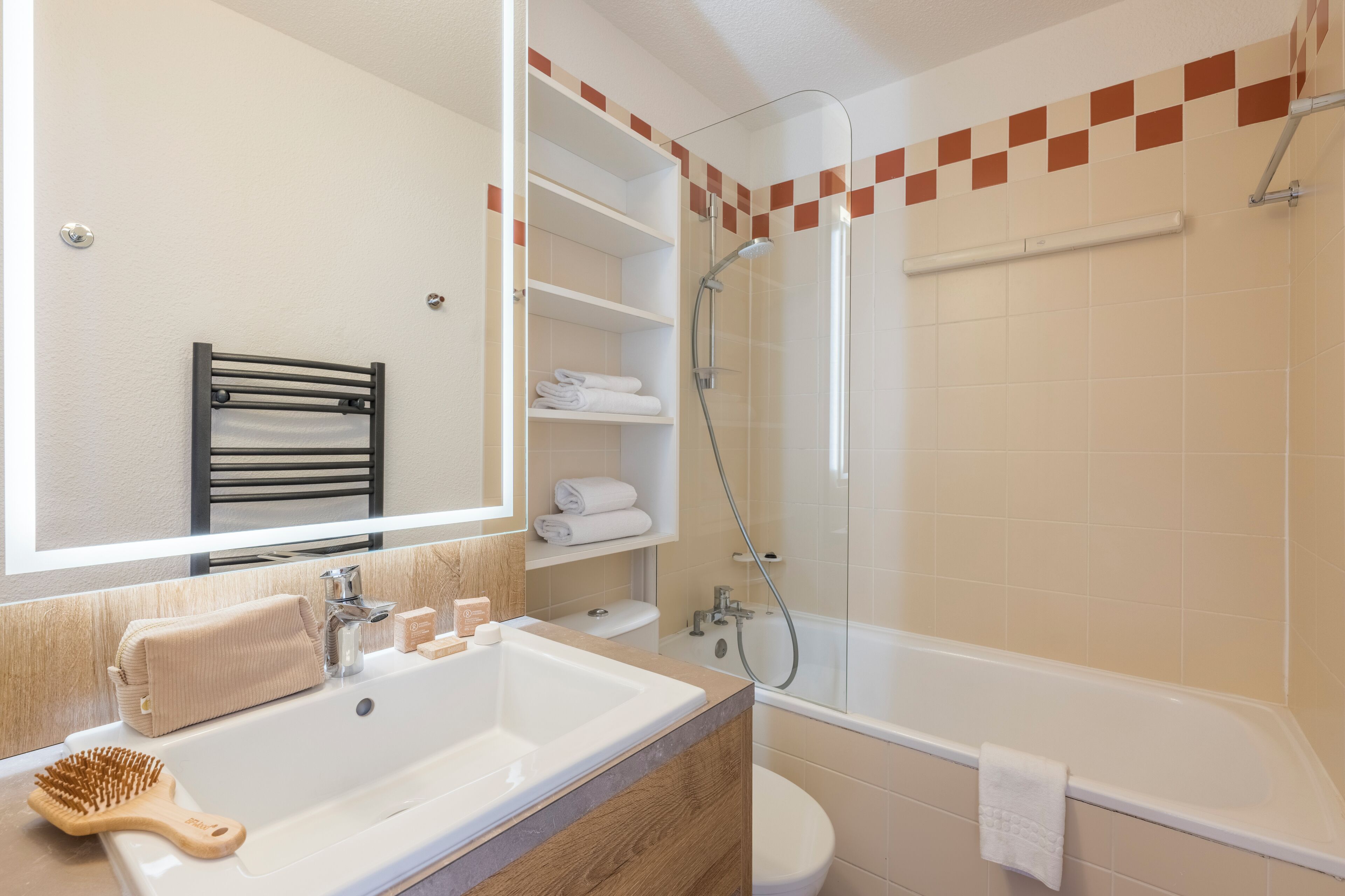 A modern bathroom with a large sink, a mirror, a towel rack, a shower, and a toilet.