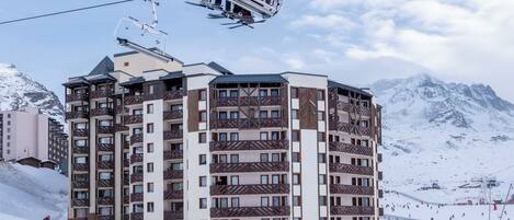 A multi-story hotel with a ski lift in the background.