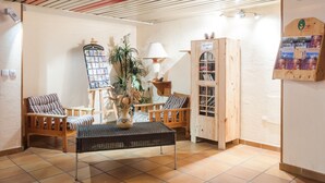 Un vestíbulo acogedor con muebles de madera, un mostrador de recepción, un panel informativo en la pared y suelo de baldosas.