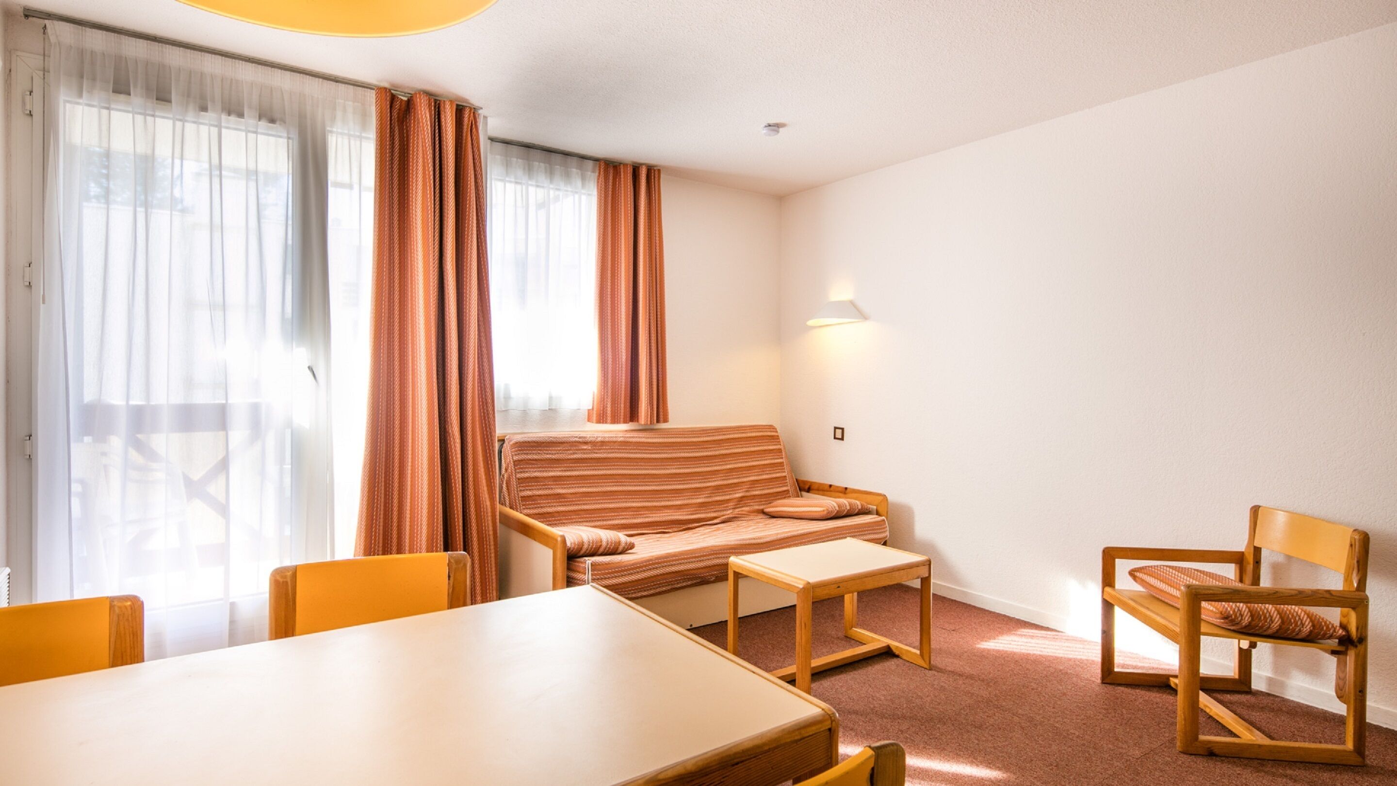 Habitación de hotel con sofá, dos sillas, una mesita y una lámpara.