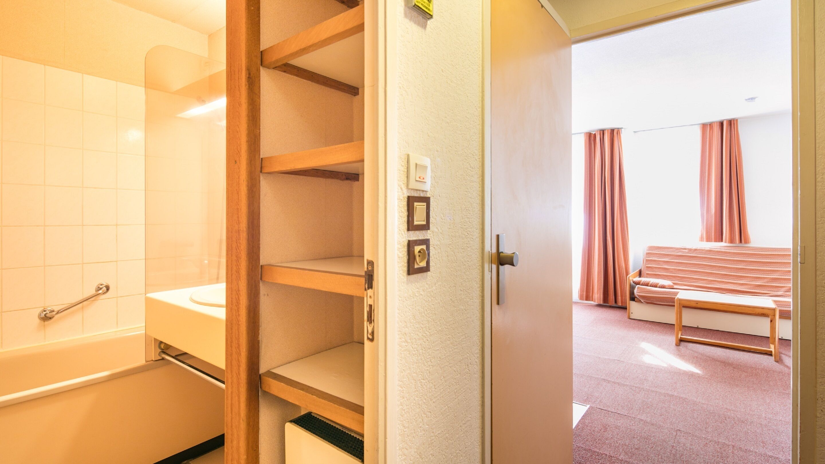 A hotel room with a bathroom, a bed, and a view of the outside.