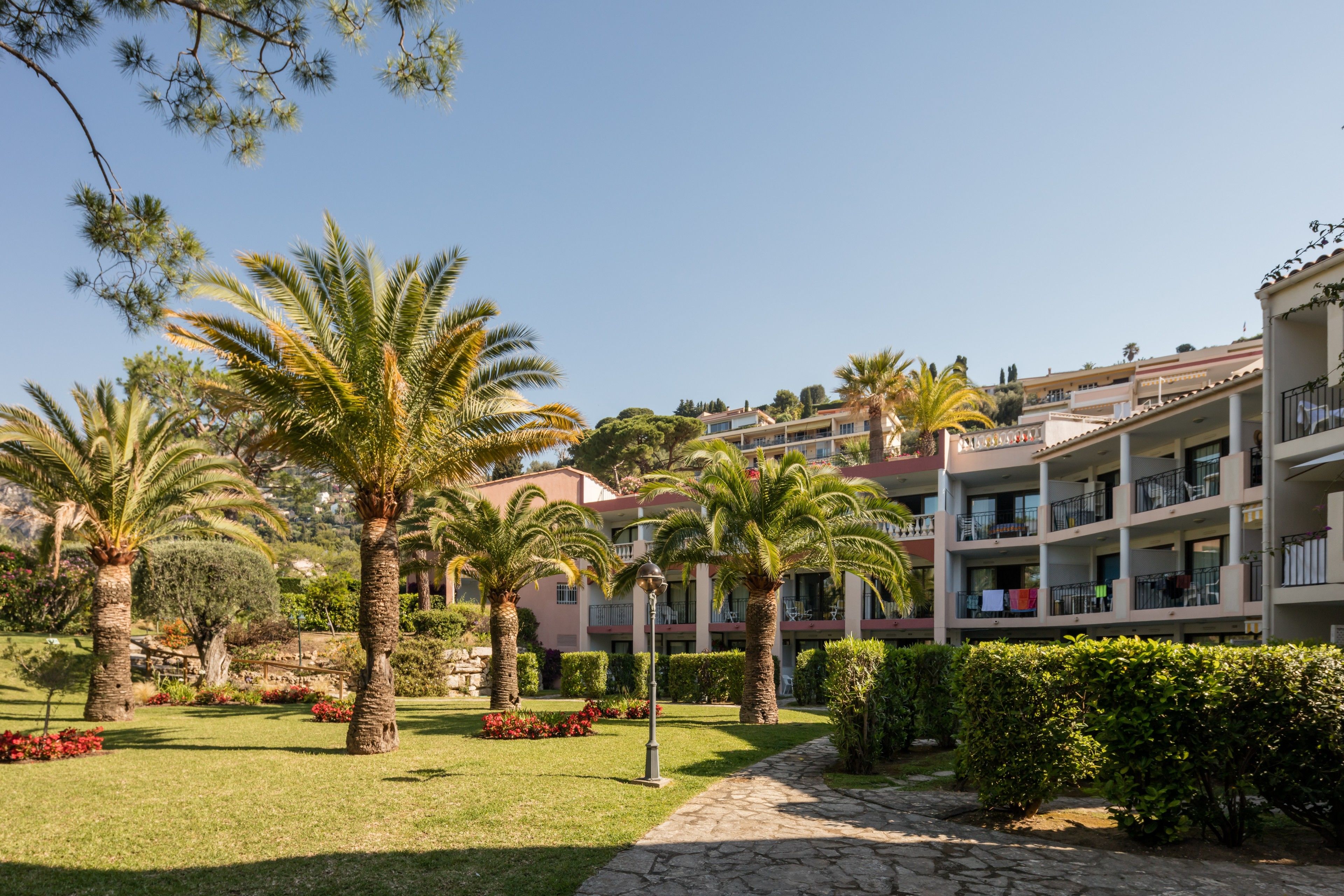 Un hôtel doté d’un jardin agrémenté de palmiers et de haies bien entretenues.