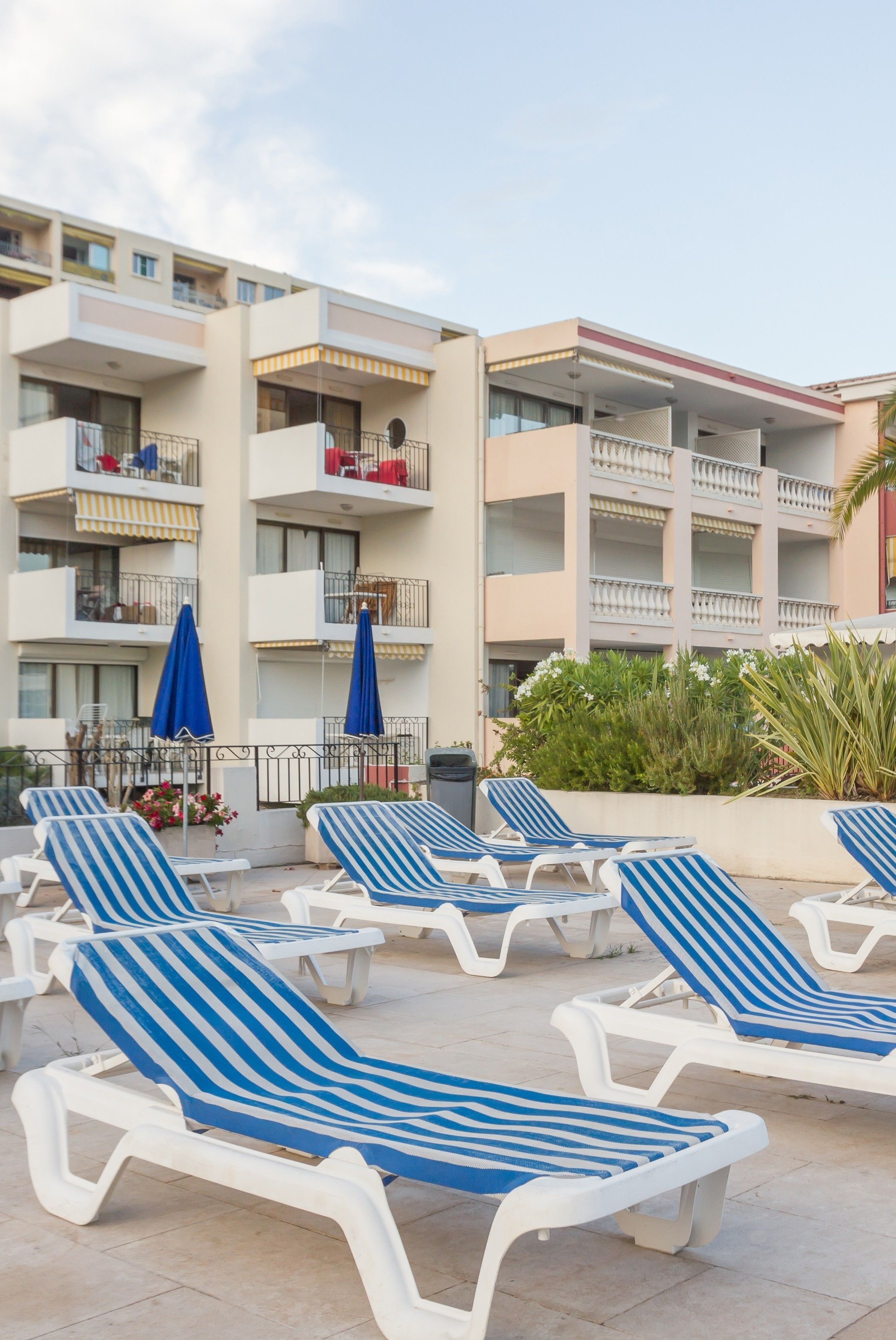 Un hotel con varios balcones, sillas de lounge al aire libre y sombrillas.