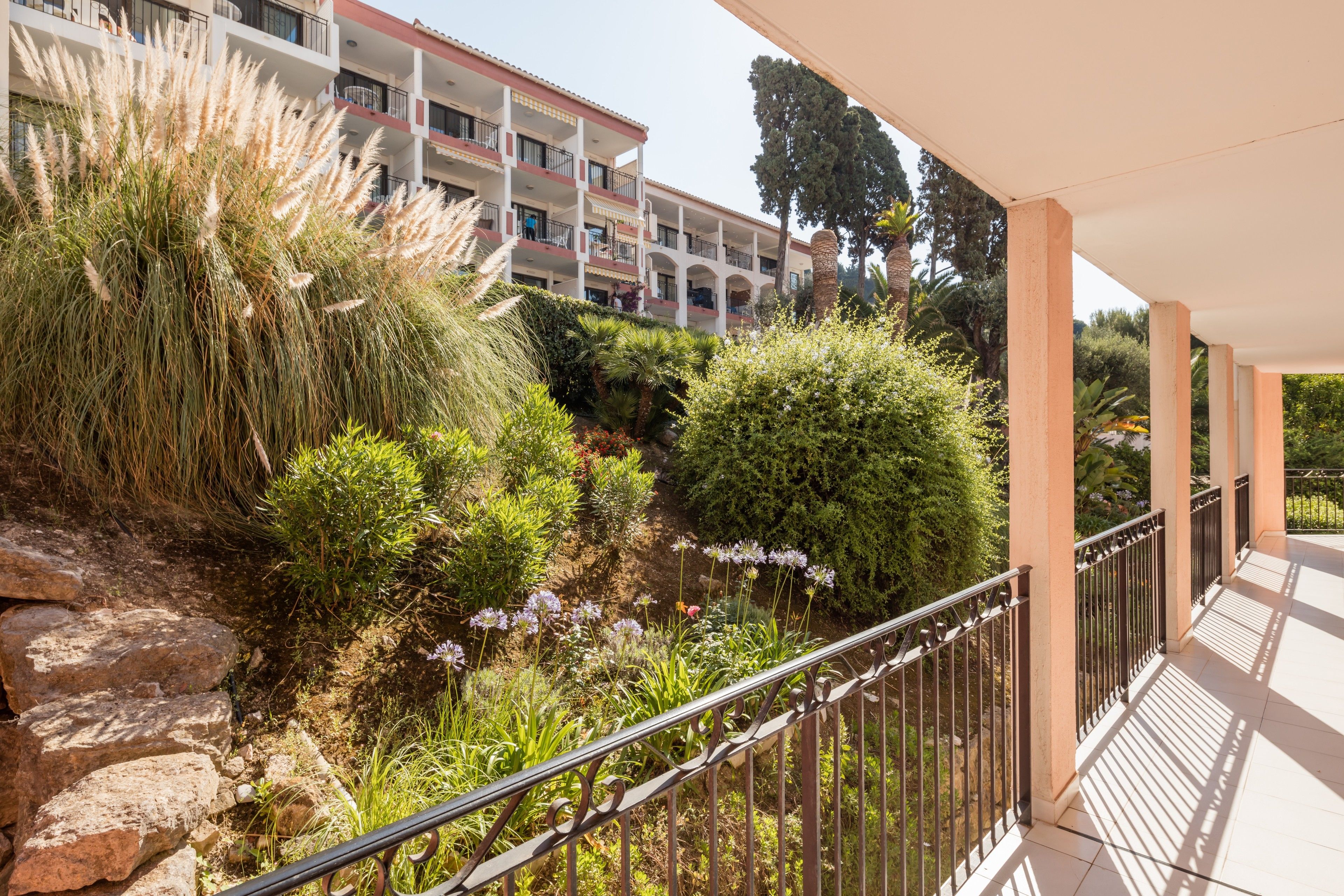 Un balcone con ringhiera, un muro in pietra e un edificio con balconi sullo sfondo.
